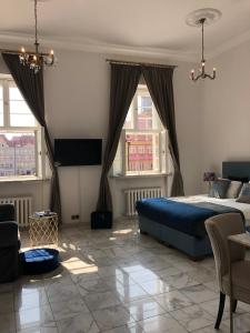 ein Schlafzimmer mit einem Bett und einem Fernseher und zwei Fenstern in der Unterkunft APARTAMENT 6 Rynek in Breslau