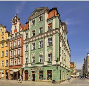 a green and white building with people walking in front of it at APARTAMENT 6 Rynek in Wrocław