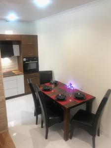 a dining room table with black chairs and a kitchen at Apartament Centrum Zakopane in Zakopane