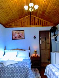 a bedroom with two beds and a wooden ceiling at Chale Ideal in Conceição da Ibitipoca