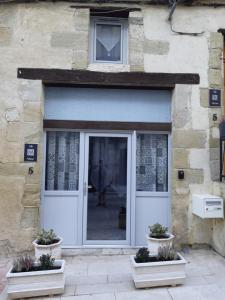 uma porta da frente de um edifício de pedra com vasos de plantas em le studio d'Oihana em Lauzun