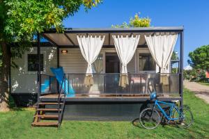 Camping Adria Mobile Home Park Umag في أوماغ: دراجة متوقفة أمام منزل صغير