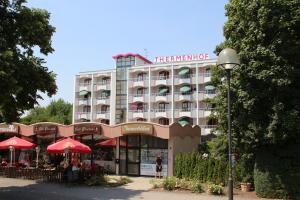 un bâtiment d'hôtel avec des parasols rouges devant lui dans l'établissement Appartmenthaus Thermenhof, à Bad Füssing