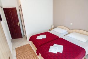 a bedroom with two beds with red sheets and white pillows at Vila Mitrovic in Budva
