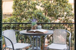 a table with a book and chairs on a balcony at Stylish, comfy apartment by Konnect, Corfu city center in Corfu