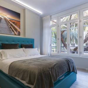 Un dormitorio con una cama azul con una pintura en la pared en A Casa Martínez B&B, en Valencia