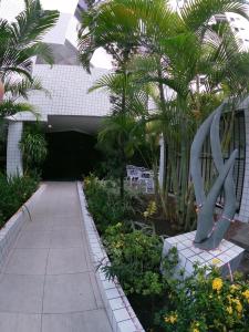 un giardino con panchina e palme e un vialetto di Golden Point a Recife