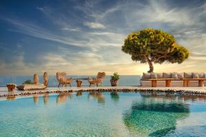 a pool with chairs and a table and a tree at San Marino Suites by Calm Collection in Fira