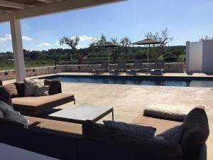 a patio with couches and chairs and a pool at HelloApulia - Trullo Bello in Martina Franca