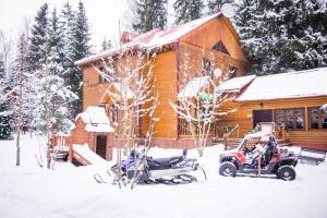 una cabaña con una moto de nieve estacionada frente a ella en Istra Holiday Hotel, en Trusovo