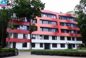 a red and white building with trees in front of it at AQUA Apartamentai prie AQUA PARKO in Druskininkai