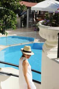 a woman wearing a hat standing next to a swimming pool at AÇELYA OTEL in Bodrum City