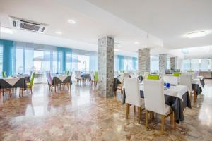 a dining room with tables and chairs and windows at Hotel Columbus in Caorle