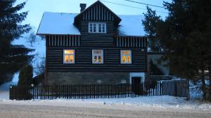 une maison noire avec des lumières de Noël dans les fenêtres dans l'établissement Chalupa na Jelení, à Jelení