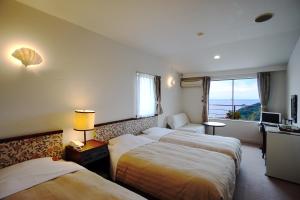 a hotel room with two beds and a window at Gardenvilla Shirahama in Shimoda