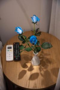 a table with a vase with three blue roses on it at Onar Modern Luxury Apartments in Kavála
