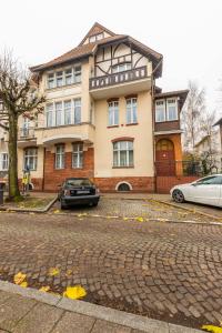 uma casa com dois carros estacionados em frente em Victus Apartamenty, Victus Apartament Fiord em Sopot