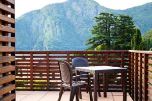 a table and chairs on a balcony with mountains in the background at Residence Lenno in Lenno