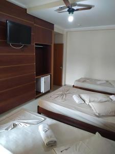 a bedroom with two beds and a tv on the wall at Hollywood Palace Hotel in Aparecida