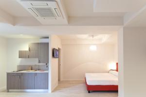 a white room with a bed and a kitchen at Residence Lenno in Lenno
