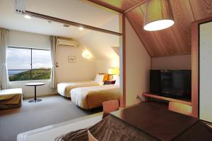 a hotel room with two beds and a flat screen tv at Gardenvilla Shirahama in Shimoda