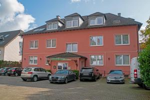 un gran edificio rojo con coches estacionados en un estacionamiento en Hotel Lonac, en Duisburg