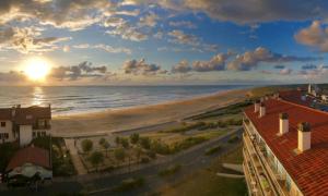 uma vista para uma praia com o pôr-do-sol em Vue superbe sur l’océan, la plage à vos pieds ! em Soorts-Hossegor