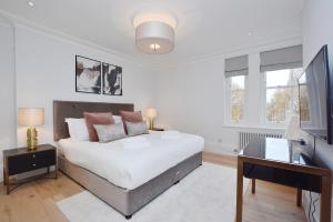 una camera con letto, scrivania e TV di Elysian House - Kensington Serviced Apartments a Londra