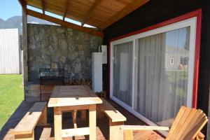 ein Picknicktisch und zwei Stühle auf einer abgeschirmten Veranda in der Unterkunft El Descanso del Quijote in Riñinahue