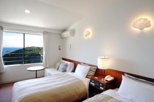 a hotel room with two beds and a window at Gardenvilla Shirahama in Shimoda