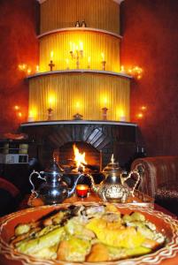 a plate of food on a table with a fireplace at Dar Calme Chez El Bouhali in Skoura