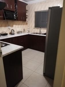 a kitchen with brown cabinets and a black refrigerator at Rocky Ridge Guest House 2 SELF CATERING - No Alcohol allowed in Roodepoort