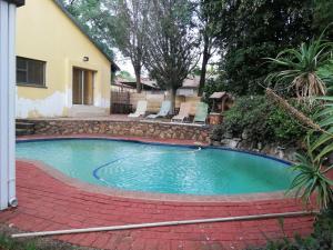 a swimming pool with chairs and a house at Rocky Ridge Guest House 2 SELF CATERING - No Alcohol allowed in Roodepoort