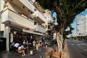 un grupo de personas sentadas en mesas fuera de un edificio en Cucu Hotel, en Tel Aviv