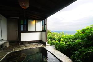a bath tub with a view of the ocean at Gardenvilla Shirahama in Shimoda