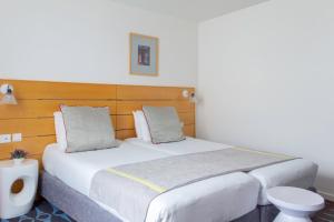 a bedroom with a large white bed with a wooden headboard at Hotel Lorette - Astotel in Paris