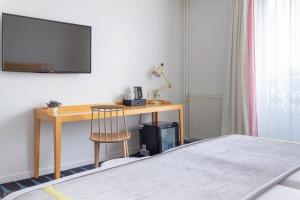 a bedroom with a desk with a television and a chair at Hotel Lorette - Astotel in Paris