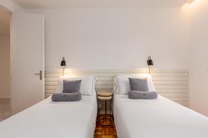 two white beds sitting next to each other in a room at Feel Porto Vintage Townhouses in Porto