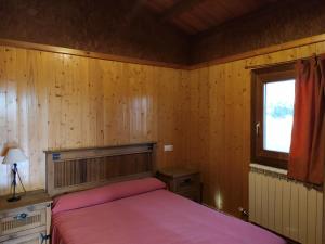 a bedroom with wooden walls and a bed with pink sheets at Camping Casa Fausto Cerca de Dinopolis in Formiche Alto