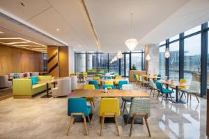 um restaurante com mesas, cadeiras e janelas em Holiday Inn Express Wuxi Taihu New City, an IHG Hotel em Wuxi