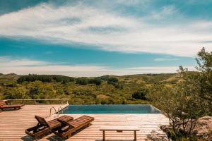 una terraza de madera con bancos y una piscina en Camino el Portal del Alma, en El Edén