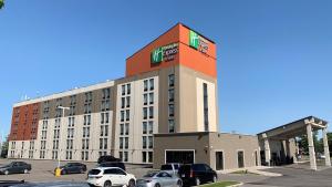 un grande edificio con auto parcheggiate in un parcheggio di Holiday Inn Express & Suites Toronto Airport West, an IHG Hotel a Mississauga