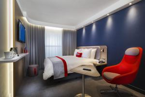 a hotel room with a bed and a red chair at Holiday Inn Express - Stockport, an IHG Hotel in Stockport