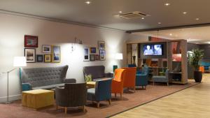 a waiting room with chairs and a tv on a wall at Holiday Inn Runcorn M56 Junction 12, an IHG Hotel in Runcorn