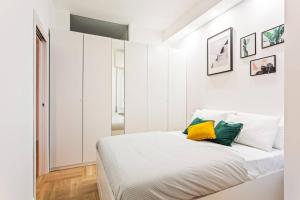 a white bedroom with a bed with colorful pillows at Easylife - Milano - D'Annunzio - Navigli in Milan