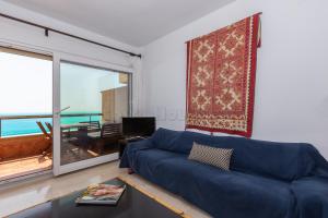 - un salon avec un canapé bleu et une grande fenêtre dans l'établissement Los Reales 8C, à Estepona