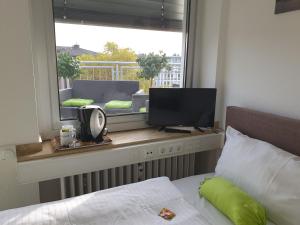 um quarto com uma cama e uma janela com uma televisão em Studiotel TOP LOFT em Düsseldorf