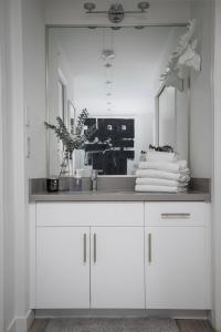 a white bathroom with a sink and a mirror at The Modern Whistler Apartment - Ski-in ski-out in Whistler
