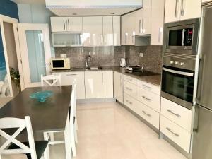 a kitchen with white cabinets and a black counter top at Seafront Levante Beach Blueline in Benidorm +19 photos