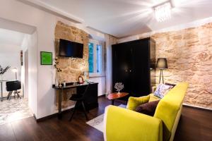 una sala de estar con sillas amarillas y una pared de piedra. en Hotel Heritage Forza, en Baška
